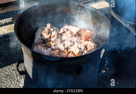 Morceaux de viande cuisant dans un grand chaudron Banque D'Images