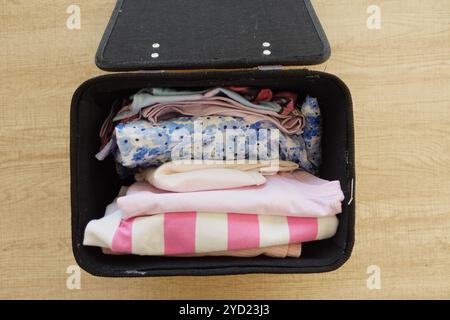 Vêtements soigneusement emballés disposés dans une élégante valise noire pour vos prochains voyages Banque D'Images