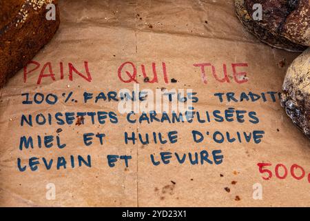 Un signe français décrivant du pain avec de la farine T65, noisettes caramélisées, miel, huile d'olive et la levure au levain. Vue close up on a market stall Banque D'Images