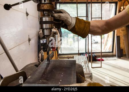 Metalworker utilise la perceuse d'établi dans l'atelier Banque D'Images