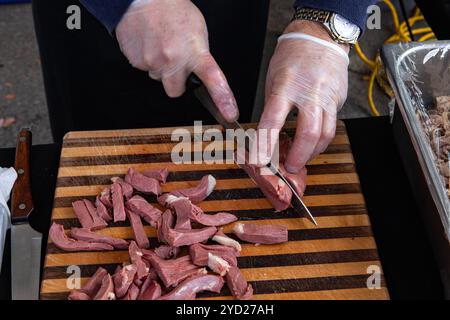 Une vue rapprochée sur les mains d’un cuisinier à l’aide d’un couteau pour préparer du foie ou du foie gras de canards engraissés sur un stand de commerçants Banque D'Images