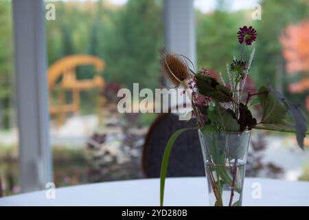 Bouquet de fleurs dans un pot de jardinière en verre, représenté sur une table blanche fantaisie Banque D'Images