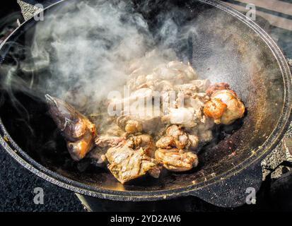 Appétissants morceaux de viande cuisant dans un grand chaudron Banque D'Images