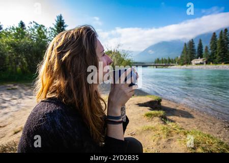 Femme pensive buvant du café dans la nature Banque D'Images