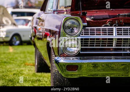 Piscine selective focus vintage American muscle voiture rouge la moitié avant, côté gauche, ouvrez le capot, Close up sur les projecteurs lumière lampe et bouclier, calandre chromée Banque D'Images