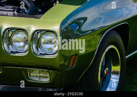 Old vintage American green muscle car la moitié côté avant droit, à l'ouvrir le capot et close up sur les phares avant s'allument des lampes, avec grande roue rim Banque D'Images