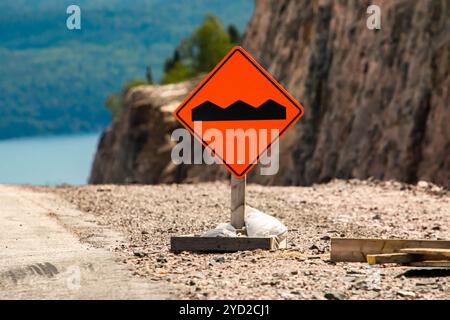 Route cahoteuse ou inégale signe orange sur le terrain dans la mise au point sélective, condition temporaire signalisation routière Banque D'Images