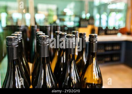 Des bouteilles de vin en verre ambré foncé dessus, le joint et l'épaule close up portrait vue, de nouvelles bouteilles avec bouchon à visser noir sur une ligne d'embouteillage winery Banque D'Images