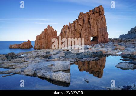 Une vue des roches rouges d'Arbatax avec des reflets dans les bassins de marée au premier plan Banque D'Images