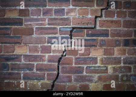 Une grande fissure dans un vieux mur de briques rouges Banque D'Images