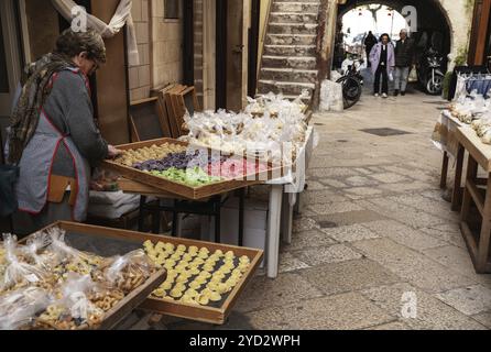 Bari, Italie, 27 novembre 2023 : une femme fabriquant de pâtes dépose ses produits dans l'emblématique Strada del Orecchiette dans la vieille ville de Bari Vecchio, en Europe Banque D'Images