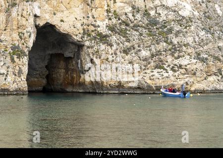 Dwejra, Malte, 19 décembre 2023 : pêcheur transportant des touristes à travers l'arc naturel de la mer intérieure sur l'île de Gozo à Malte lors d'une excursion en bateau, Europ Banque D'Images