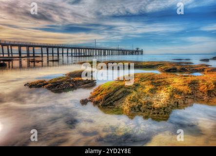 Le point Lonsdale Pier en silhouette avec des rochers au premier plan, péninsule de Bellarine, Victoria, Australie Banque D'Images