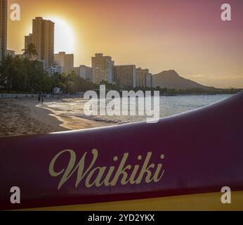 Un canoë hawaïen traditionnel sur Waikiki Beach au coucher du soleil Banque D'Images