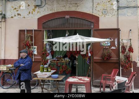 Bari, Italie, 27 novembre 2023 : magasin du coin à Bari Vecchio avec un vieil homme vendant des piments et des olives, Europe Banque D'Images