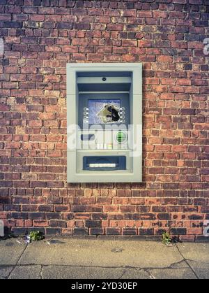 A Vandalized ATM Against A Grungy Red Brick Wall Stock Photo