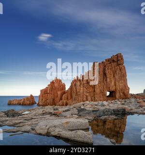 Une vue des roches rouges d'Arbatax avec des reflets dans les bassins de marée au premier plan Banque D'Images