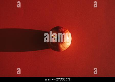 Pomme rouge formant une ombre contre le dos rouge Banque D'Images