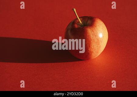 Pomme rouge formant une ombre contre le dos rouge Banque D'Images