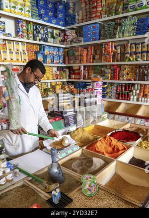 Er-Rich, Maroc, 7 mars 2024 : commerçant marocain mélangeant des épices dans sa boutique du marché d'er-Rich, Afrique Banque D'Images