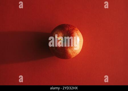 Pomme rouge formant une ombre contre le dos rouge Banque D'Images