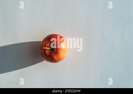 Pomme rouge formant une ombre sur le dos blanc Banque D'Images