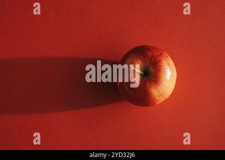 Pomme rouge formant une ombre contre le dos rouge Banque D'Images