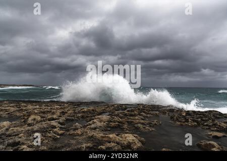 Des vagues de tempête s'écrasant sur les rives rocheuses de Pembroke Beach à Malte sous un ciel couvert Banque D'Images