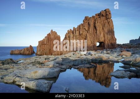 Une vue des roches rouges d'Arbatax avec des reflets dans les bassins de marée au premier plan Banque D'Images