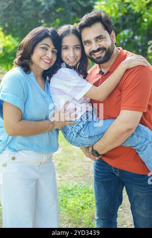 Jeune famille indienne heureuse appréciant dans le parc d'été ou le jardin. père portant, tenant sa fille sur l'épaule. vacances ou vacances. Parents avec chil Banque D'Images