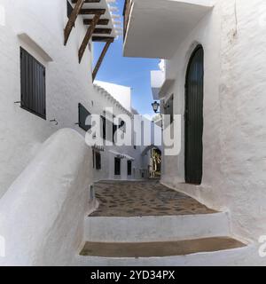 Binibeca Vell, Espagne, 24 janvier 2024 : ruelle étroite menant à travers un labyrinthe de bâtiments blanchis à la chaux dans le centre du village de Binibeca Vell, en Europe Banque D'Images