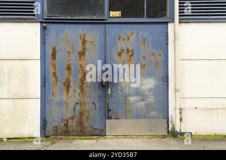 Vieille porte en métal bleu rouillé avec peinture endommagée et corrosion, une image de pourriture et d'abandon Banque D'Images