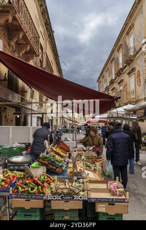 Syracuse, Italie, 28 décembre 2023 : Greengrocer vend des fruits et légumes à des clients sur le marché de Syracuse, en Europe Banque D'Images