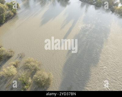 Vue aérienne de l'eau boueuse qui coule sur les rives du Pô couvrant les terres environnantes, avec quelques arbres et buissons luttant pour survivre après lourd Banque D'Images