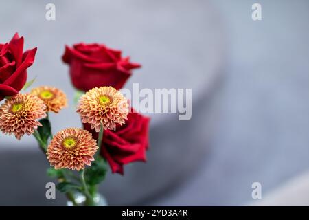 Un beau vase qui est élégamment rempli de roses rouges vibrantes et de fleurs oranges joyeuses, créant un affichage vivant et coloré Banque D'Images