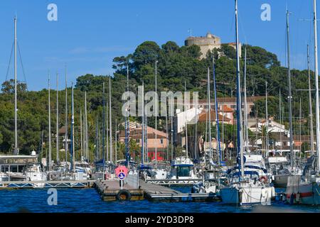 France, Porquerolles, 9 juin 2024 : bateaux dans le port de l'île de Porquerolles, et Fort Sainte Agathe Banque D'Images