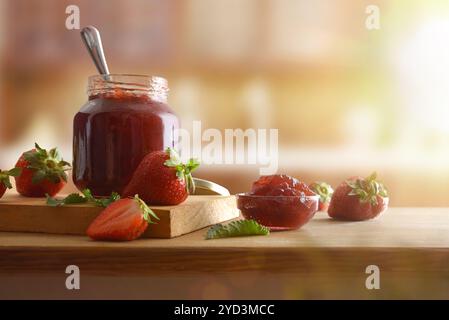 Pots avec confiture de fraises sur bois et fruits autour d'une table en bois et fond de cuisine rustique. Vue de face. Banque D'Images