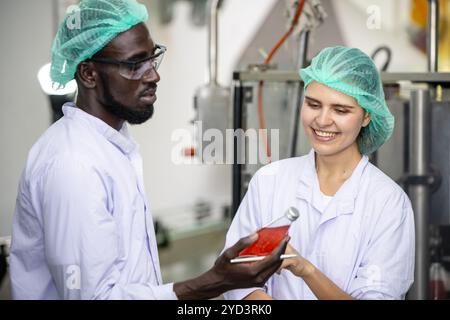 L'équipe de travailleurs de contrôle de la qualité du personnel de contrôle de qualité de l'usine de boissons à boire travaille. Le responsable de l'hygiène vérifie l'inspection des processus standard dans la production de l'usine Banque D'Images