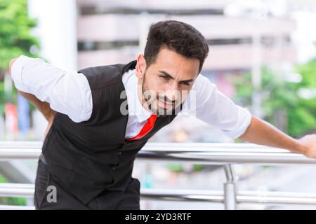 Hispanique indien homme d'affaires muscle joindre la douleur dans le bas du dos du syndrome de bureau après une dure journée de travail. Banque D'Images