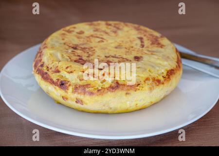 Tortilla espagnole classique entière connue sous le nom de tortilla de patatas, spécialité traditionnelle de base faite avec des ingrédients simples comme des pommes de terre, des oignons et des œufs Banque D'Images