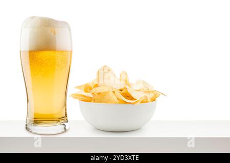 Verre de bière lager avec des chips de pomme de terre sur la table blanche. Banque D'Images