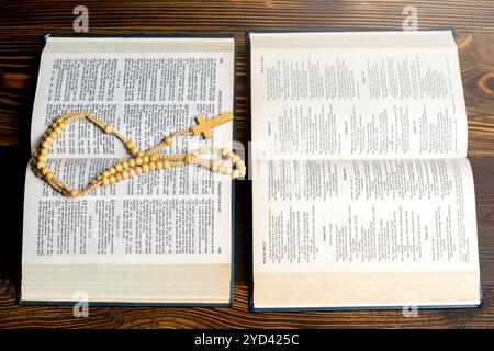 Livre ouvert de la Sainte Bible et perles de chapelet. Il est allongé sur la table. Symbole de foi et de culte en Dieu. Service religieux chrétien, vacances ou concept Banque D'Images