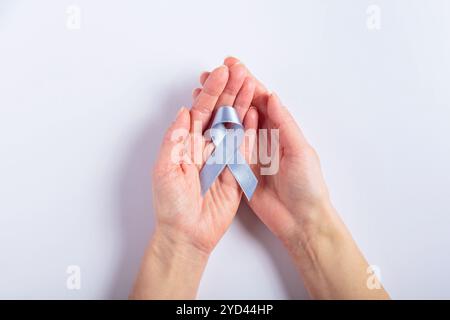 Ruban cancer colorectal tenu par les mains féminines sur blanc Banque D'Images