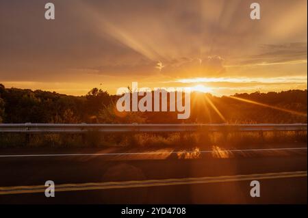 Coucher de soleil plein d'espoir avec lumière parasite et rayons de soleil le long de la route Banque D'Images