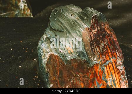 Grande pierre avec des coins rugueux dans le jardin ZEN en pierre. Une roche brune grise avec des bords tranchants et une surface texturée sur un sable noir. Pierres naturelles roches Banque D'Images