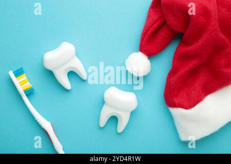 Dents blanches avec chapeaux de père noël sur fond bleu. Dentiste joyeux Noël et concept du nouvel an. Vue de dessus, pose à plat. Banque D'Images