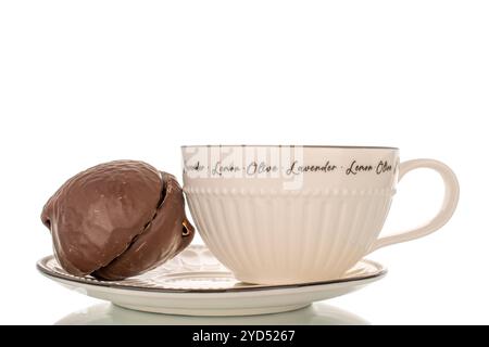 Guimauve au chocolat sur soucoupe en céramique avec tasse, macro, isolé sur fond blanc. Banque D'Images