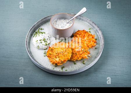 Crêpes de pommes de terre au panais traditionnelles avec ciboulette et sauce au fromage blanc servies en gros plan sur une assiette Nordic Design avec espace texte Banque D'Images