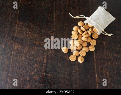 Petit sac de jute avec Kruidnoten sur table en bois, confiserie traditionnelle hollandaise consommée habituellement en décembre autour de la fête des Sinterklaas Banque D'Images