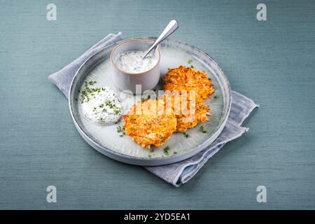 Crêpes de pommes de terre au panais traditionnelles avec ciboulette et sauce au fromage blanc servies en gros plan sur une assiette Nordic Design avec espace texte Banque D'Images